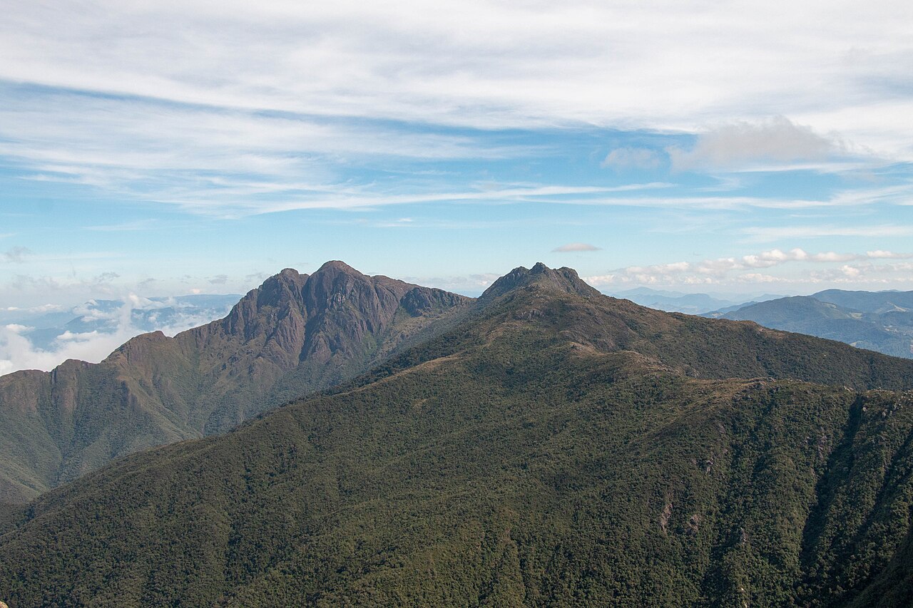 Pico dos Marins e o Marinzinho vistos à distância, com os paredões rochosos acima da mata.
