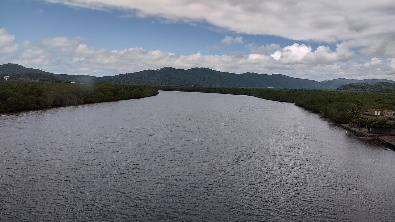 Rio Itapanhaú, largo e de águas escuras, entre margens de mata em Bertioga.