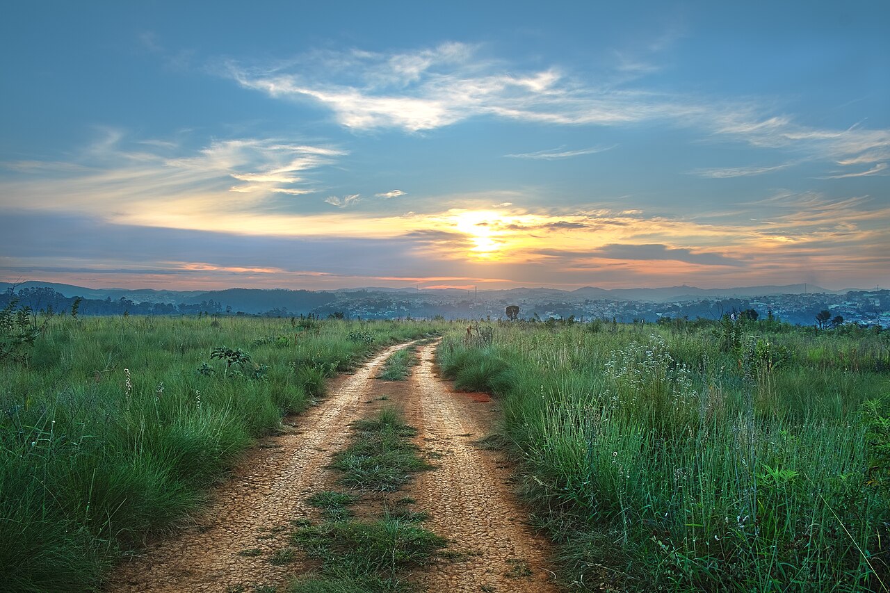 Estrada de terra entre campos ao entardecer, na região do mirante do Juquery.