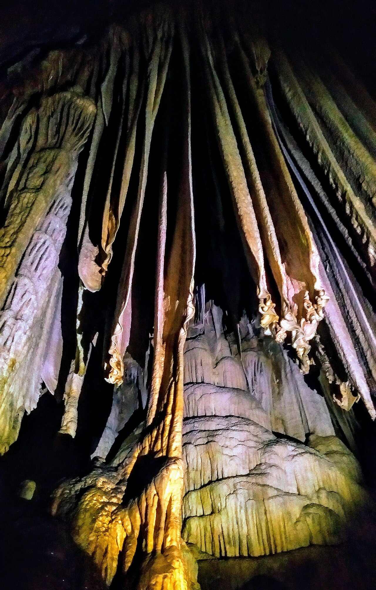 Colunas e cortinas de pedra iluminadas no interior da Caverna do Diabo.