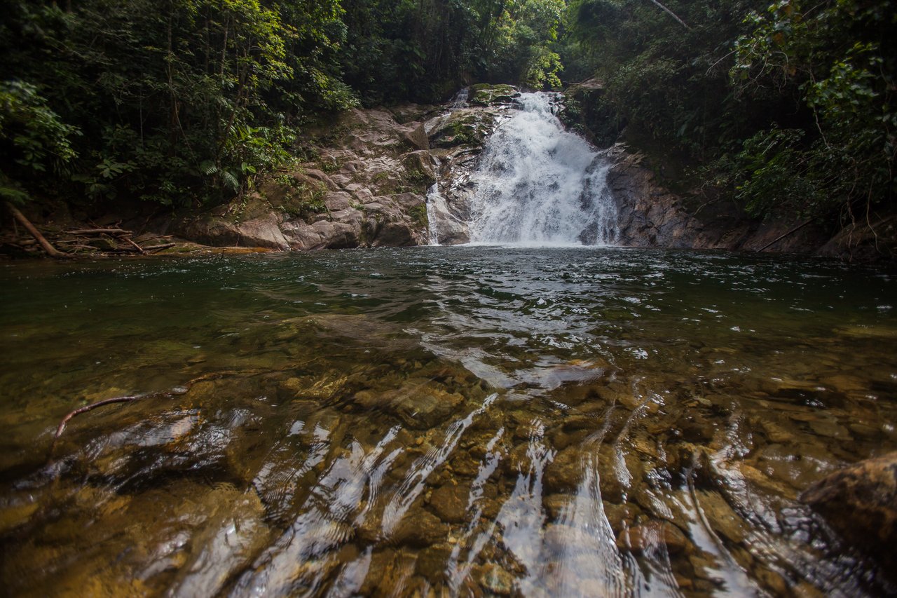 Cachoeira do Ribeirão de Itu descendo sobre a rocha para um poço de águas claras, com pedras visíveis no fundo