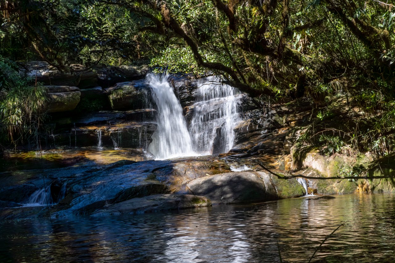 Cachoeira do Rio Bonito caindo sobre lajes de pedra em um poço, sob a copa das árvores do Núcleo Cunha