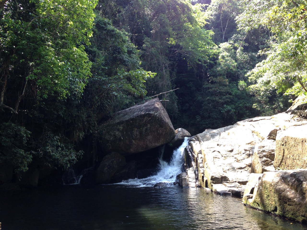 Cachoeira da Escada: água caindo em degraus de pedra ao lado de um grande bloco de rocha, em um poço cercado de mata